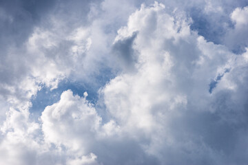 Blue sky with large white cumulus clouds. Dramatic cloudscape background, natural weather pattern, soft daylight atmosphere, open sky texture for design and environmental themes.