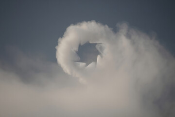 Cloud formation with star shaped hole, foggy atmosphere, sky background for overlay or texture