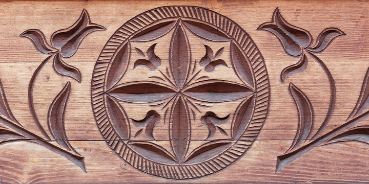Carved wood architectonic detail of wall. Folklore decorative hexafoil and flowers motif.
