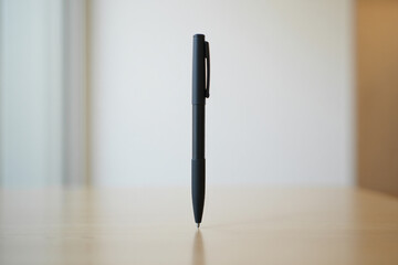 Black pen standing upright on wooden desk in office