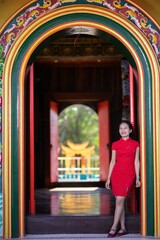 Elegant Young Woman in Red Dress at Traditional Colorful Archway