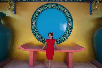Young Girl in Red Dress Posing in Vibrant Cultural Environment