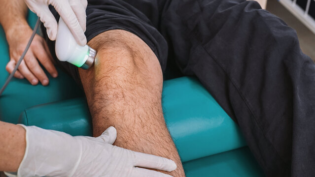 Ultrasound therapy applied to knee during physiotherapy session. Handheld transducer delivers sound waves to soft tissue, improving circulation, reducing pain, supporting muscle and joint recovery
