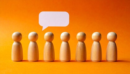Wooden peg dolls standing with a white speech bubble on an orange background representing communication concept