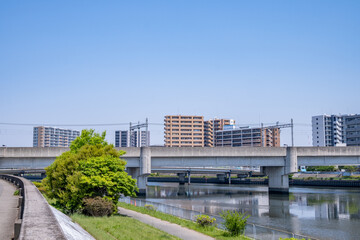 都市部の高架橋と高層マンションが映る河川の風景