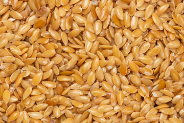 Plie of golden raw flax seeds for background.