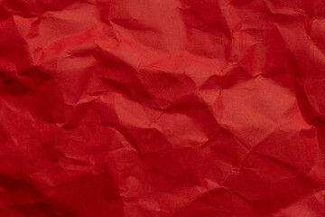 Fototapeta premium Crumpled Red Paper Texture Background,A close-up, top-down view of vibrant red crumpled paper texture. The irregular folds and creases create a dramatic play of light and shadow, perfect for abstract 