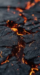 Close-up of black rock, cracked open with fiery orange lava flowing through