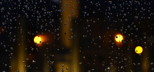 Backlit drops on a glass screen wit circle lights as background