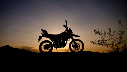 Obraz premium Motorcycle Silhouette at Sunset: Capturing Adventure and Freedom. A sleek motorcycle silhouette is framed against a stunning sunset, evoking a sense of adventure and freedom