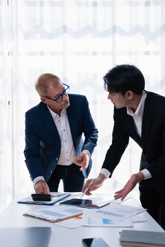 Business partners collaborating in a meeting, reviewing financial data on documents and a digital tablet, planning new strategies and making important decisions for their company