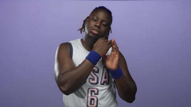 Young african american man in usa basketball jersey number 6 with hand to mouth yawning, sweatband and patch in purple studio; fatigue rest.