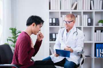 Obraz premium Patient explains symptoms to a doctor during a consultation, covering his mouth while coughing, with the doctor observing and holding a clipboard, discussing health issues in a clinic