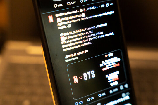 Warsaw, Poland - Feb 3, 2026: A smartphone displays a Twitter feed featuring announcements related to Netflix and BTS, highlighting engagement and promotional media events.