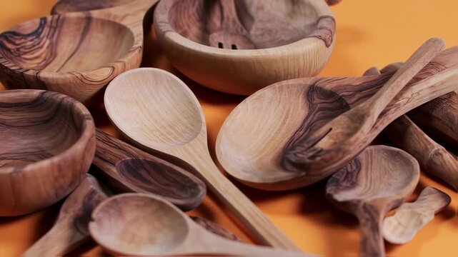 Assorted wooden bowls and spoons on an orange surface