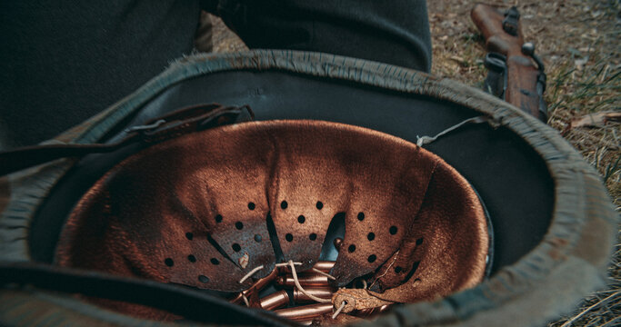 Inverted German steel helmet with ammunition cartridges inside on ground