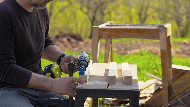 Man drilling precise hole in wooden board using pocket hole jig and cordless drill outdoors, DIY woodworking process, carpentry tools, home improvement and craftsmanship concept.