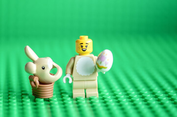 Naklejka premium Lego minifigure Easter bunny and easter egg on green background with copy space