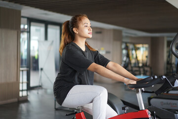 Young woman doing cardio workout on stationary exercise bike