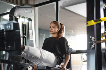 Focused woman doing leg press exercise on gym machine