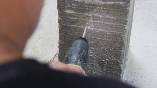 An unrecognizable worker is drilling a hole in a wall with a cordless electric drill inside an upholstery workshop in Neiva, Huila, Colombia. Concept of industry and object
