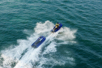 Man on jet ski towing another jet ski on the ocean.