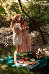Naklejka premium Two friends enjoy a picnic with diverse foods in a lush, green setting surrounded by nature on a sunny afternoon