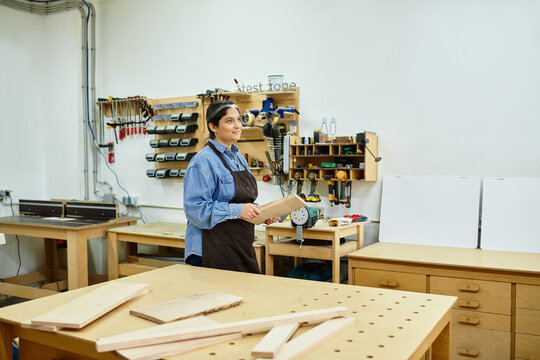 A skilled young woman works diligently in an inviting workshop, surrounded by tools and wood.