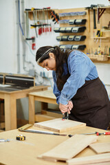 Young woman shows creativity and skill while working on her woodworking project in the workshop.