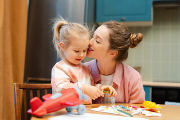 Naklejka premium Mother and daughter bonding, playing together and drawing at kitchen table