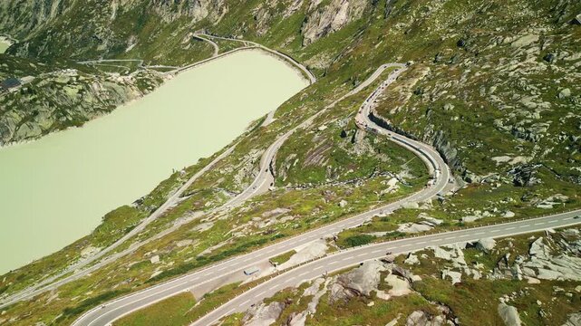 Winding roadway with moving cars in Switzerland Alps. Grimselpass in Swiss Alps
