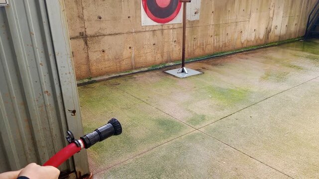 Testing water throw distance of a high pressure rubber fire hose in an industrial area.