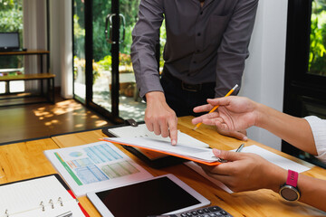 Close up of business people hands pointing at document on clipboard. Teamwork concept with advisor discussing financial plan and marketing chart at desk.