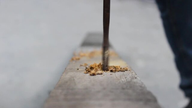 The tip of a metal drill bit is drilling a large hole in a log inside a carpentry workshop in Neiva, Huila, Colombia. Concept of industry and object 