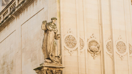 Obraz premium Old town in Italy, damaged sculpture of a saint without hands on the church, characteristic sandstone buildings in Lecce