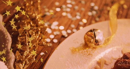 Sitting gold jingle bell on white plate at wooden table, pastry and star confetti, copy space