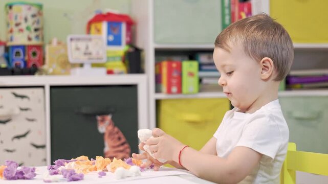 Toddler boy developing fine motor skills playing with play dough