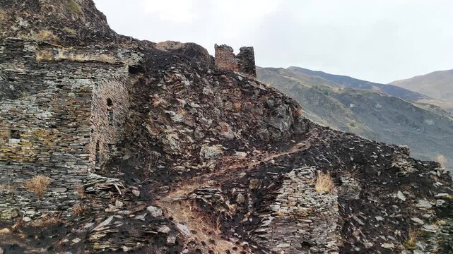 Ancient stone towers and ruins of mutso fortress built on a rocky mountain in khevsureti, georgia, showcasing medieval architecture and historical significance