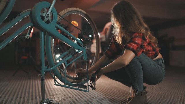 Young woman inflating bicycle tire in garage