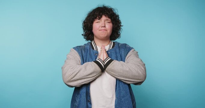 Person stands with hands together in different poses against a blue background during a short session showing expression and thought