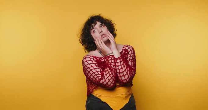 Performing different expressions in front of a yellow background during a creative art session in a studio