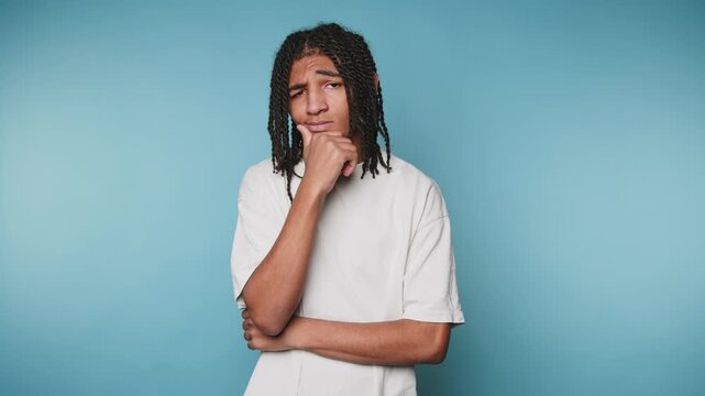 Young man poses with deep thought in front of a blue background in a studio setting