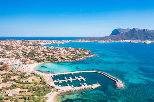 Aerial view of Baia Caddinas beach with turquoise water and resort area in Golfo Aranci, Sardinia, Italy