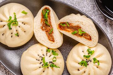Steamed buns on a dark plate.