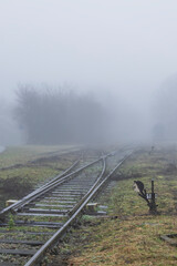 Diverging railway tracks receding into dense fog in Uhrice