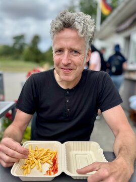 Mann beim Pommes essen im Sommer