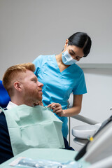 Fototapeta premium Dental assistant placing a bib on a smiling male patient in a dental clinic