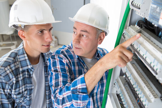 electricians connecting wires in distribution board