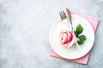 Table setting with white plate, cutlery and flowers.