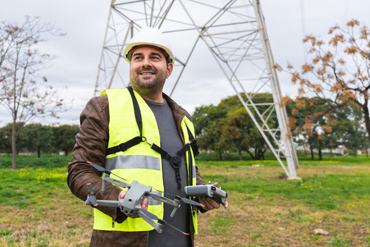 Industrial worker wearing hard hat and reflective vest holding drone and remote control